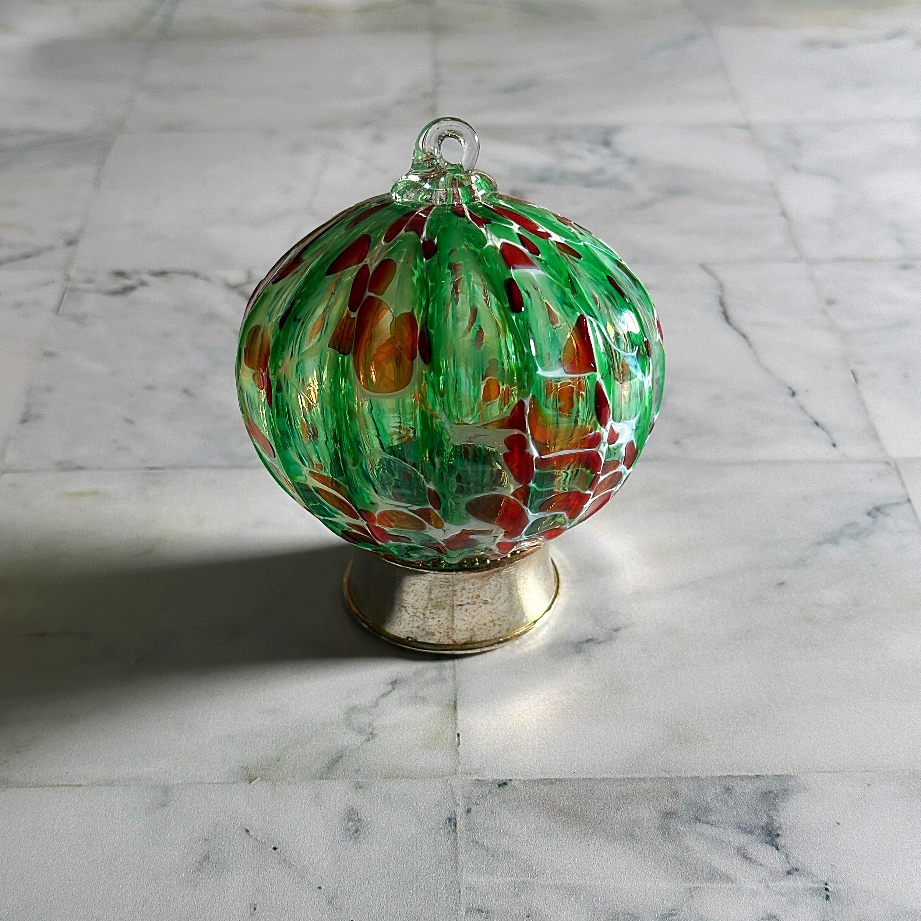 red, white and green ribbed hand-blown glass ornament on display